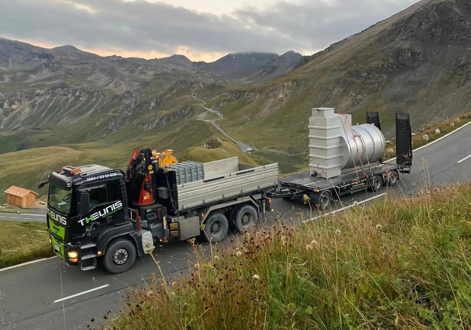 Schwarzer THEUNIS-LKW mit Ladekran und Tieflader auf einer Passstraße