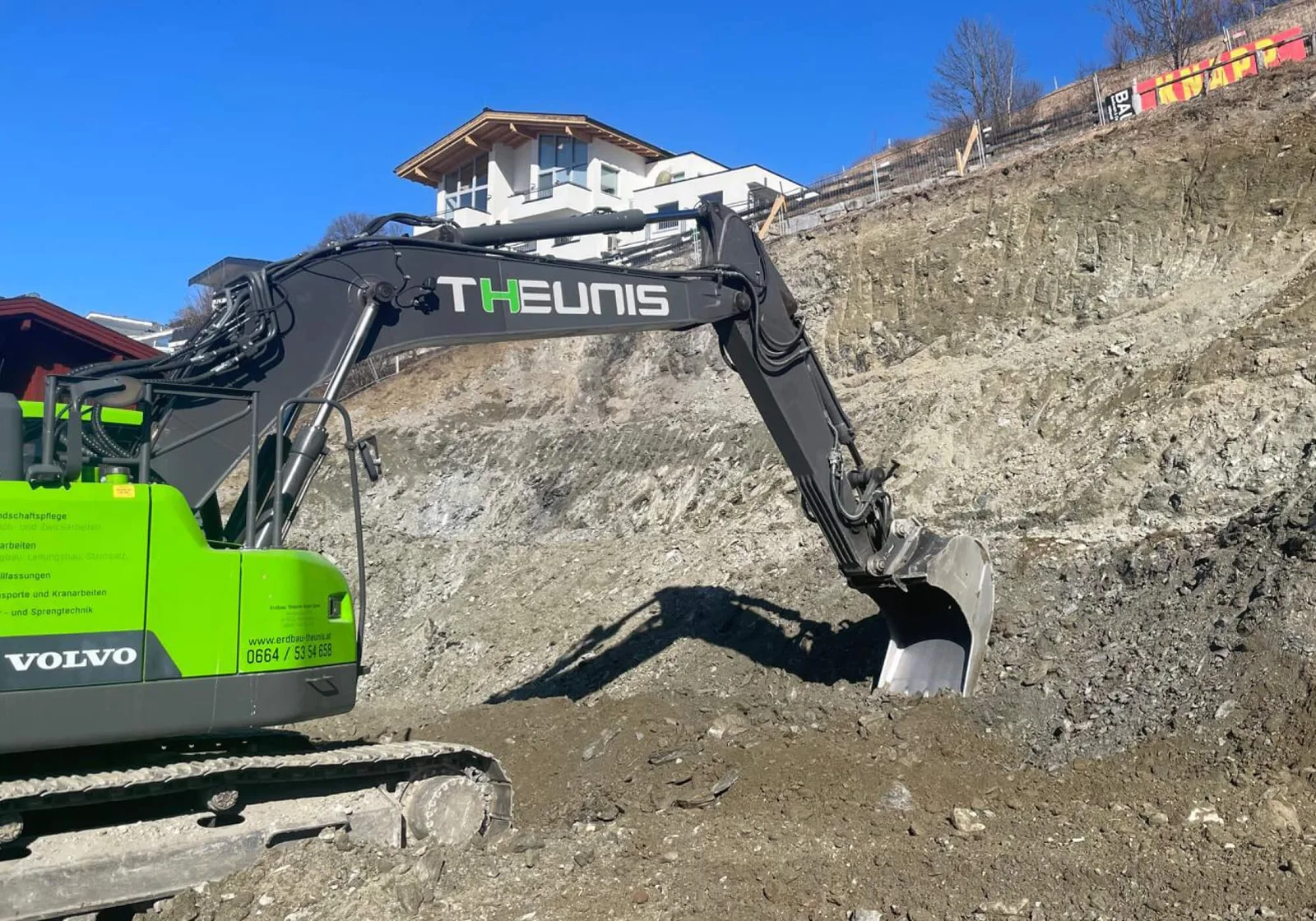 Volvo-Kettenbagger mit THEUNIS-Schriftzug in einer Baugrube am Hang