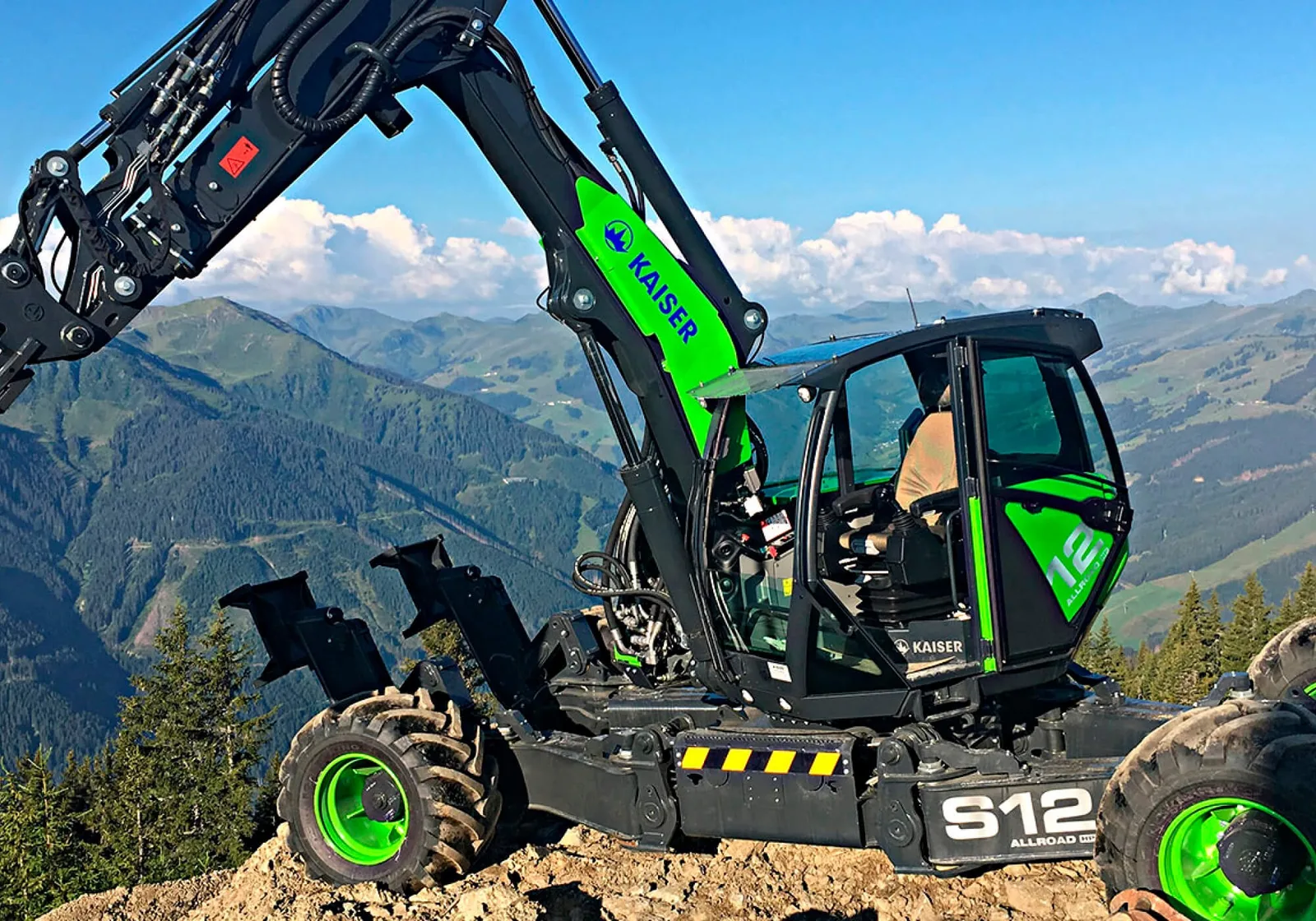 Grüner Kaiser-Schreitbagger auf einem Grat über einem weiten Bergpanorama