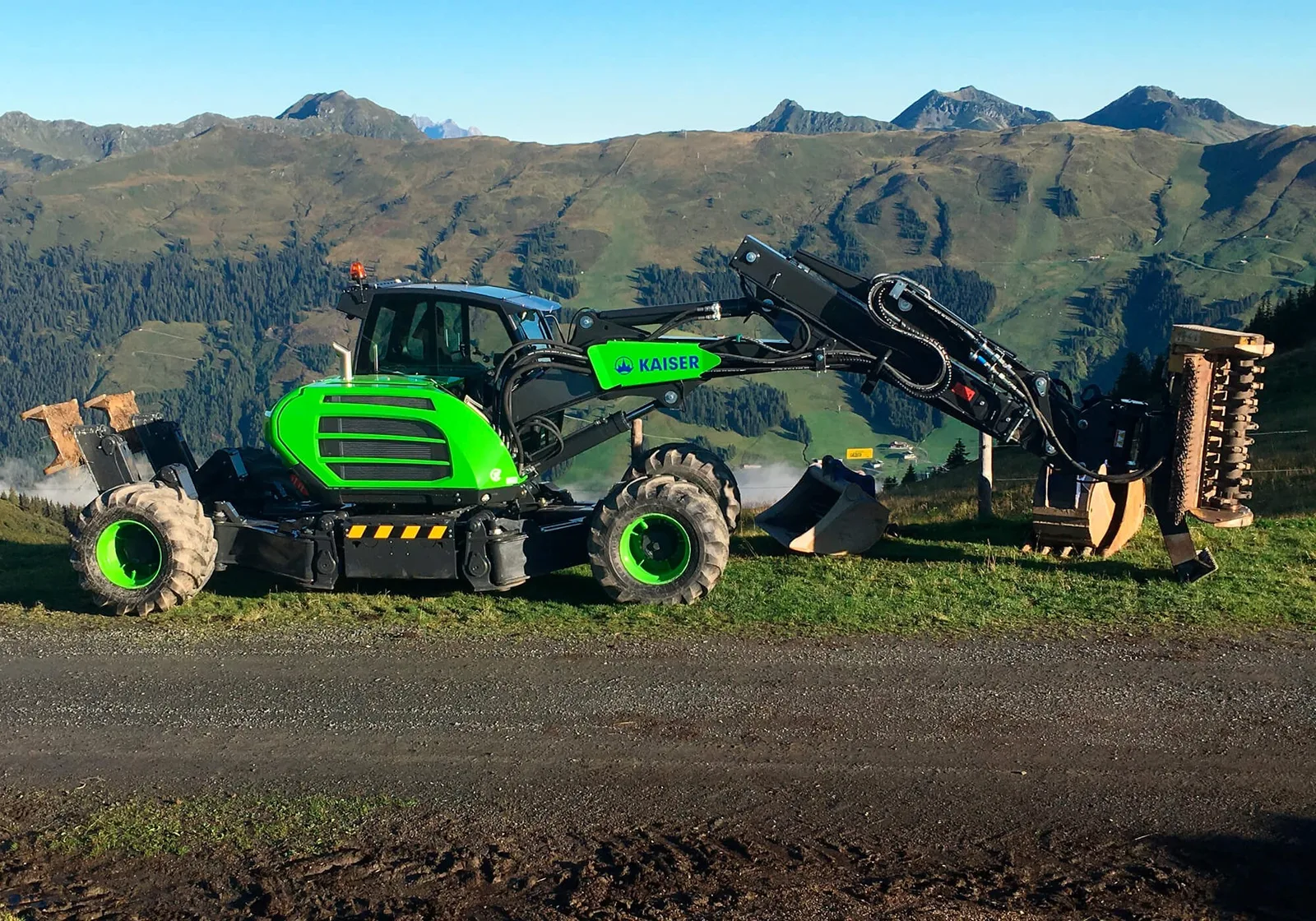 Grüner Kaiser-Schreitbagger mit Mulchkopf auf einem Almweg