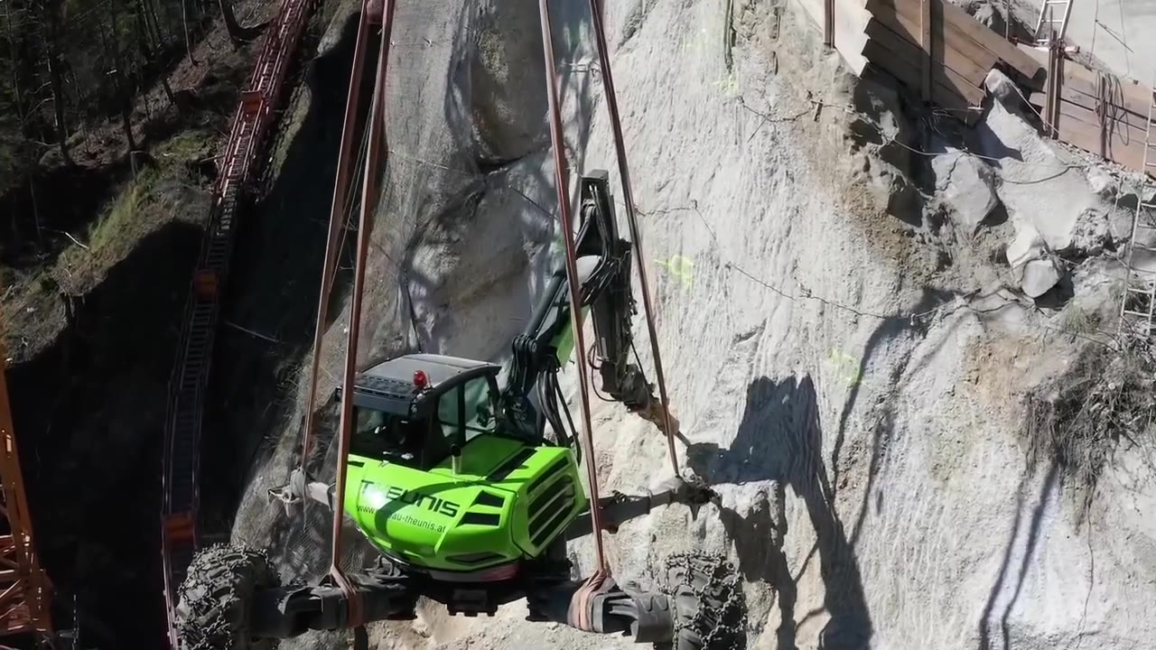 Grüner Schreitbagger von Theunis an einer steilen Felswand